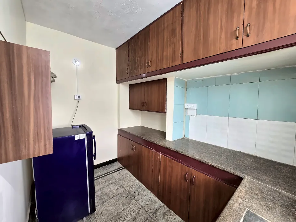 Kitchen with wooden cabinets and refrigerator in Unit 3A at Raaj Illam